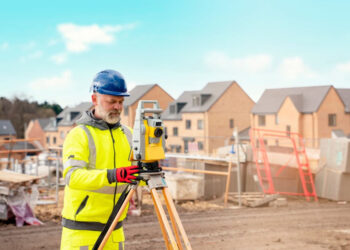 Surveyor with total station in suburban aerea